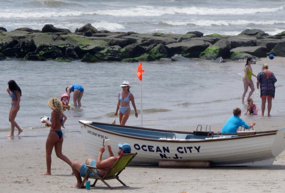 This July 8, 2021 photo shows beachgoers on the sand in Ocean City, N.J. Numerous residents of Ocean City are among those who oppose three offshore wind farms planned for the ocean off their city, fearing their impact on the ocean, the environment and the economy. (AP Photo/Wayne Parry)