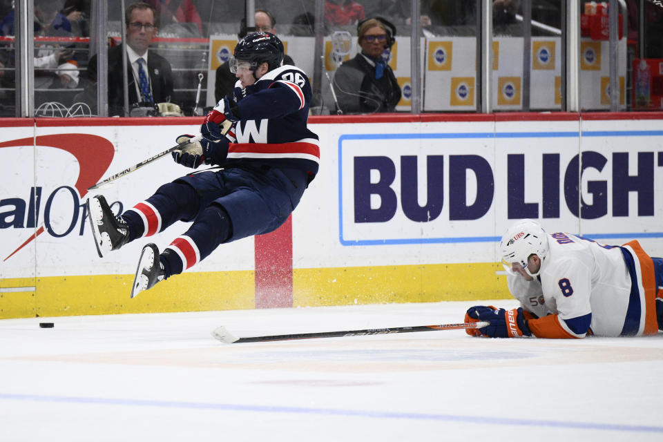 Washington Capitals right wing Nicolas Aube-Kubel, left, gets airborne past New York Islanders defenseman Noah Dobson (8) during the second period of an NHL hockey game, Monday, April 10, 2023, in Washington. (AP Photo/Nick Wass)
