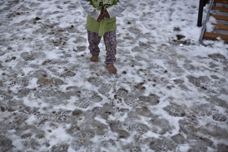 A Syrian refugee child walks barefoot on frozen ground at the refugee camp of Ritsona about 86 kilometers north of Athen on Jan. 11, 2017. Photo from The Canadian Press