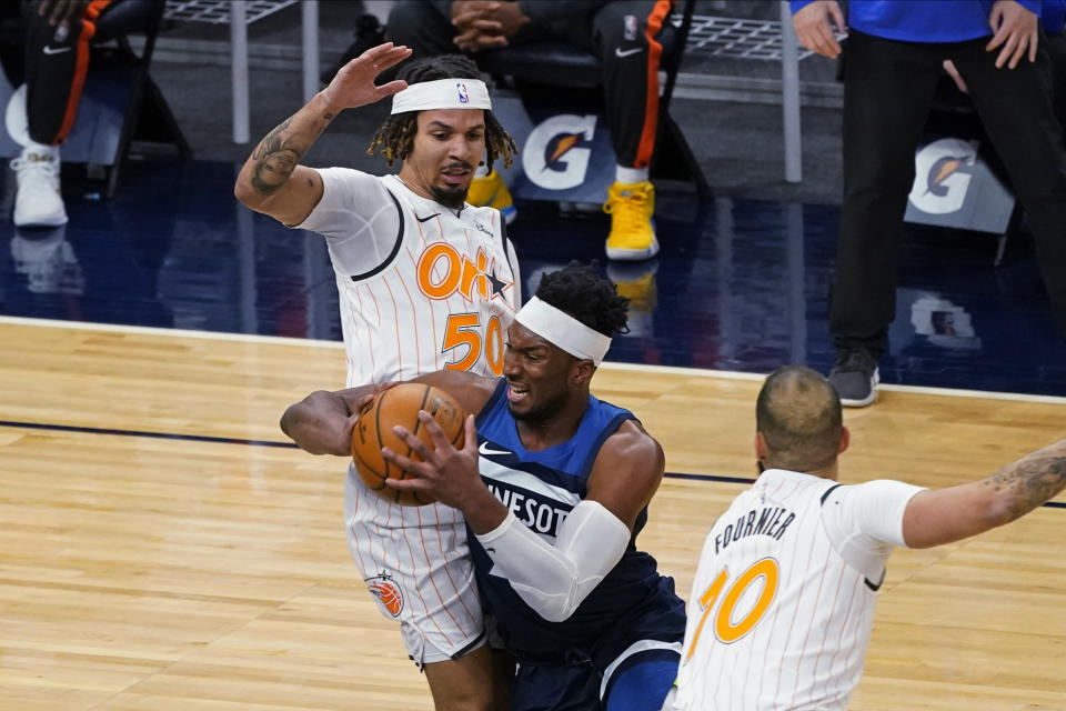 Minnesota Timberwolves' Josh Okogie, center, drives between Orlando Magic's Cole Anthony, left, and Evan Fournier during the first half of an NBA basketball game Wednesday, Jan. 20, 2021, in Minneapolis. (AP Photo/Jim Mone)