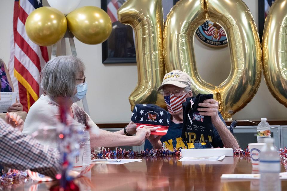 Ann Van Zandt gives her father Ralph Morris a few birthday gifts Monday as the Navy veteran celebrated his 100th birthday at the Joint Ambulatory Care Center in Pensacola.