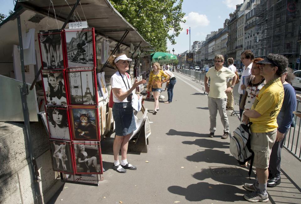 In this photo taken Friday, July 19, 2013, tour guide Shari Segall, left, speaks about Thomas Jefferson next to a book stand during a tour around the main spots of the Revolutonary-era American presence on Paris' left bank, in Paris, France. (AP Photo/Francois Mori)