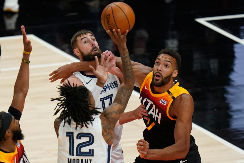 Memphis Grizzlies guard Ja Morant (12) shoots as Utah Jazz center Rudy Gobert (27) battles with Memphis Grizzlies center Jonas Valanciunas (17) during the first half of Game 2 of their NBA basketball first-round playoff series Wednesday, May 26, 2021, in Salt Lake City. (AP Photo/Rick Bowmer)