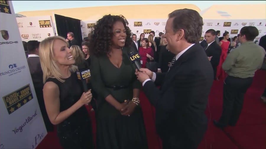 Jessica Holmes and Sam Rubin speaking with Oprah Winfrey on the red carpet. (KTLA)