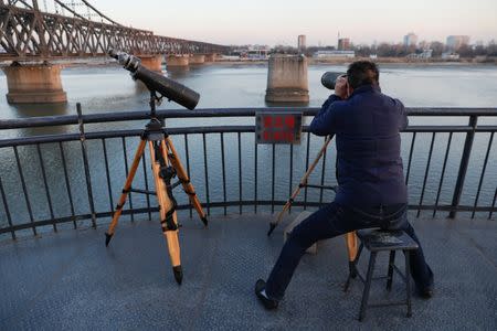 A man looks through binoculars towards North Korea from the Broken Bridge over the Yalu River connecting the North Korean town of Sinuiju and Dandong in China's Liaoning Province, November 19, 2017. REUTERS/Damir Sagolj