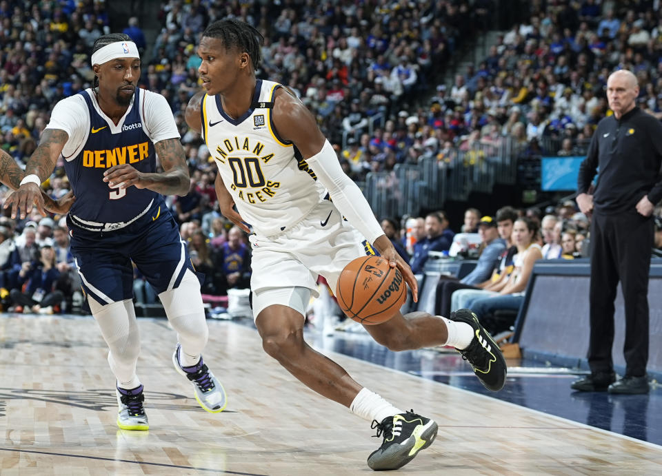 Indiana Pacers guard Bennedict Mathurin (00) drives past Denver Nuggets guard Kentavious Caldwell-Pope, left, in the first half of an NBA basketball game Sunday, Jan. 14, 2024, in Denver. (AP Photo/David Zalubowski)