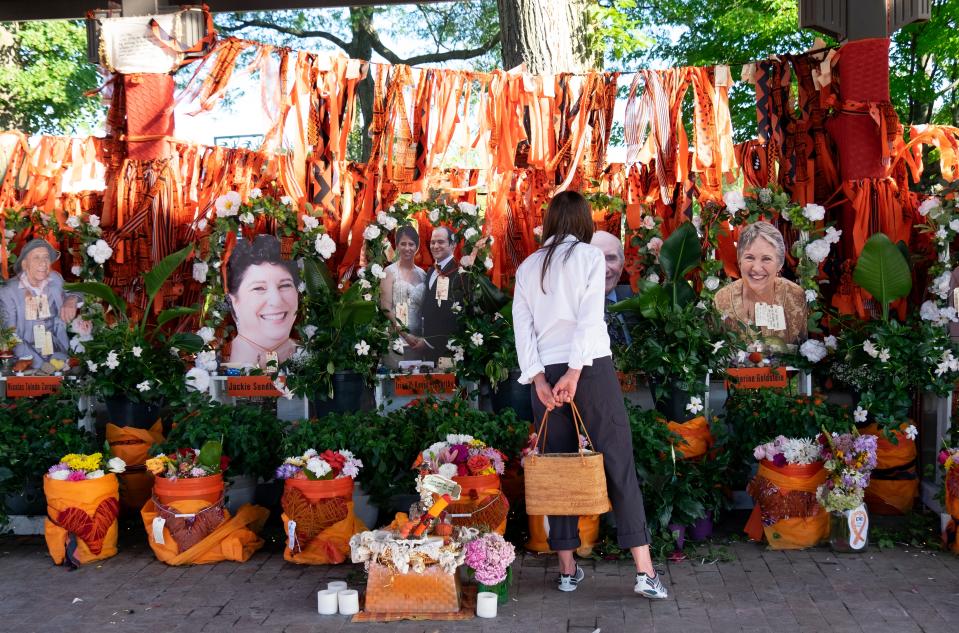 A woman stops by a memorial for the victims of the mass shooting at a Fourth of July parade in downtown Highland Park, Illinois, on Aug. 2, 2022.