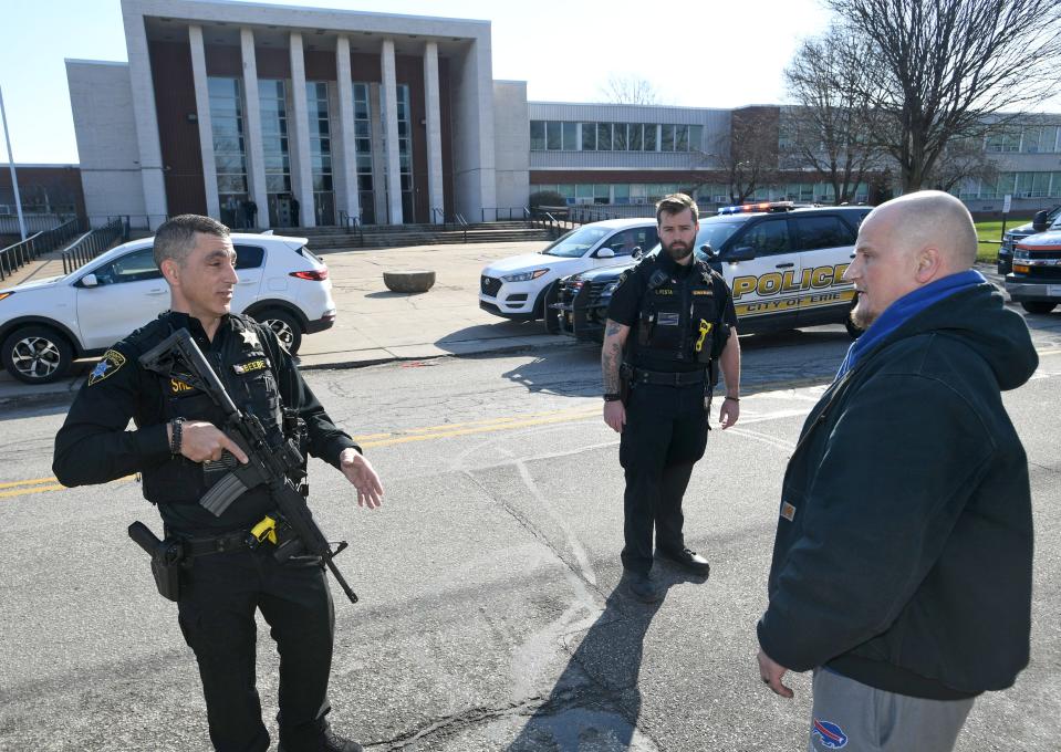 Erie County Deputy Sheriff Tommy Beebe, at left, and Deputy Sheriff Tyler Festa, background, talk with Jason Peterson, at right, following a shooting at Erie High School on Tuesday. Peterson said he was waiting for his child, who is a student at the school.