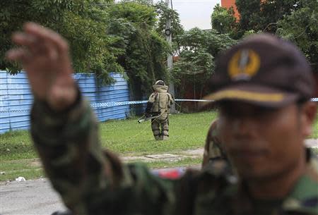 A Cambodian Mine Action Center (CMAC) personnel (C) prepares to detonate a bomb that security officials discovered outside of Cambodia's National Assembly in central Phnom Penh, September 13, 2013. REUTERS/Samrang Pring