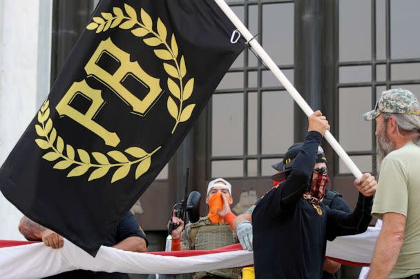 PHOTO: FILE - A protester carries a Proud Boys banner while other members start to unfurl a large U.S. flag in front of the Oregon State Capitol in Salem, Ore., Sept. 7, 2020. (Andrew Selsky/AP, FILE)