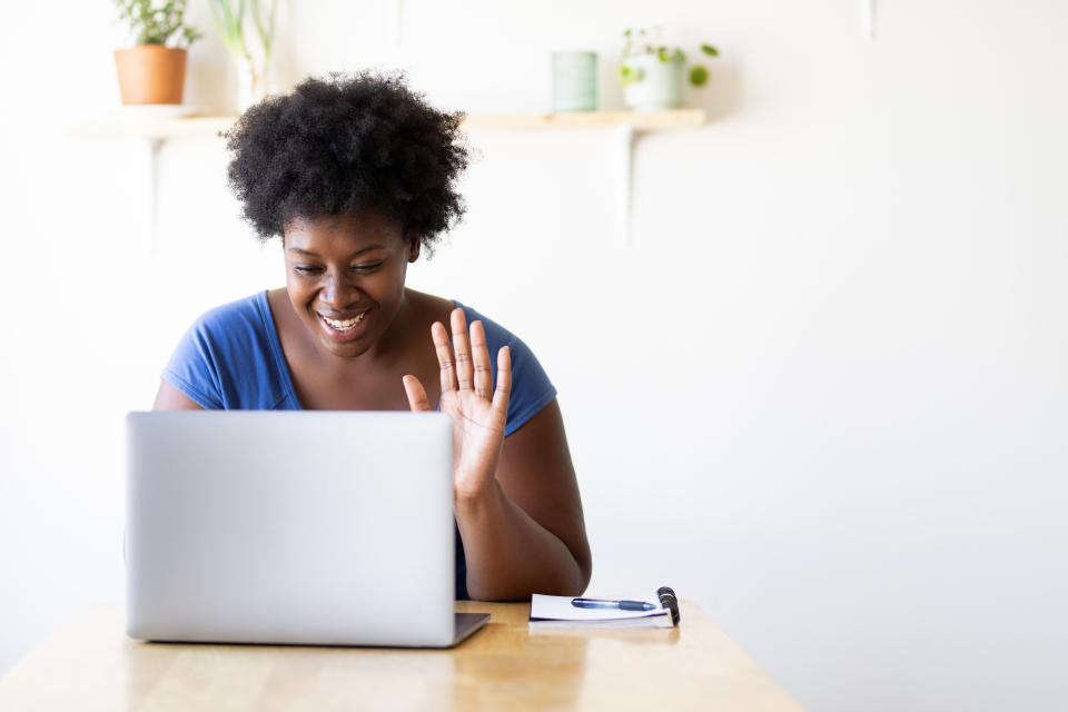 Woman at home during pandemic lockdown having video call on her laptop. Young woman video calling using a laptop.