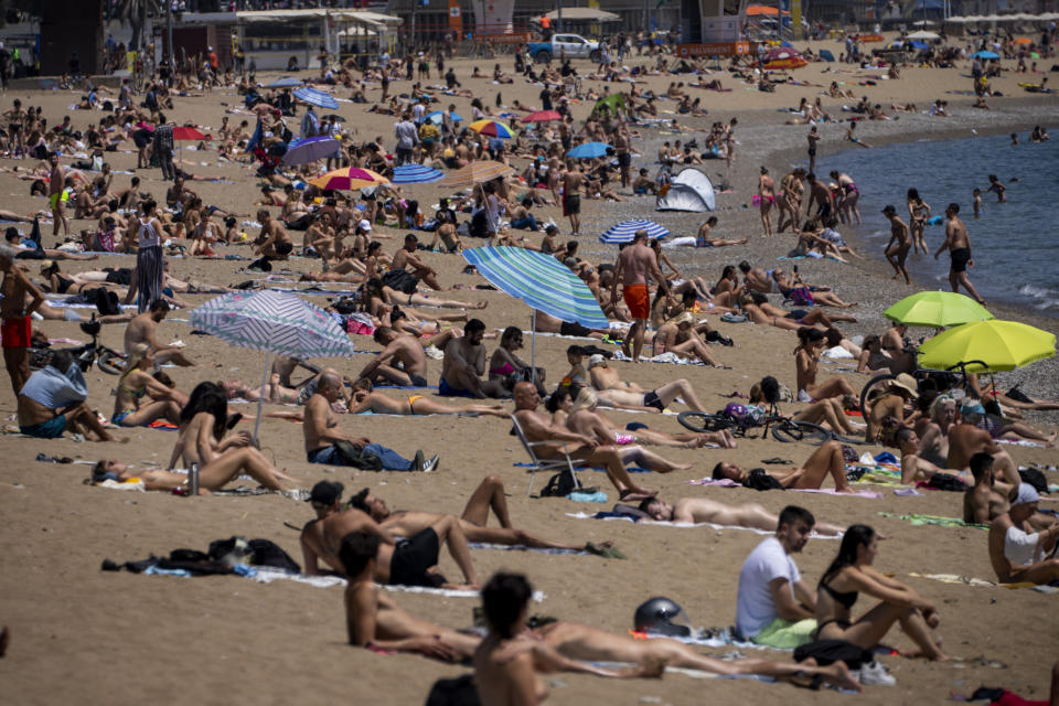 People sunbathe on the beach in Barcelona, Spain, Tuesday, June 8, 2021. Spain is jumpstarting its summer tourism season by welcoming vaccinated visitors from most countries as well as European visitors who can prove they are not infected with coronavirus. (AP Photo/Emilio Morenatti)