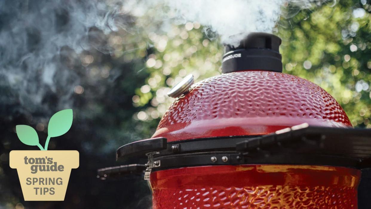  Kamado joe grill with smoke coming out of the top. 