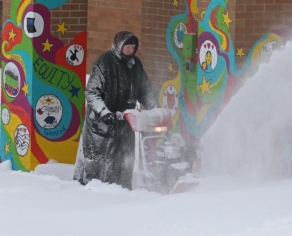Miller South custodian Dennis Sulzbach plows the entrance to the school Monday in Akron.