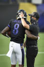 FILE - Baltimore Ravens quarterback Lamar Jackson, left, hugs head coach John Harbaugh during an NFL football training camp practice, Saturday, Aug. 29, 2020, in Baltimore, Md. They'll be playing Sunday in an empty stadium, facing a Cleveland Browns team with a new coaching staff that’s provided no clue how they plan to employ a revamped offense. “A lot of unknowns," Ravens coach John Harbaugh acknowledged. About the only thing for sure is that Baltimore quarterback Lamar Jackson, the multi-faceted reigning NFL MVP, will be the focal point of an offense that last year set a league record with 3,296 yards rushing and helped the Ravens win the AFC North with the best regular-season record in the NFL. (AP Photo/Gail Burton, FIle)