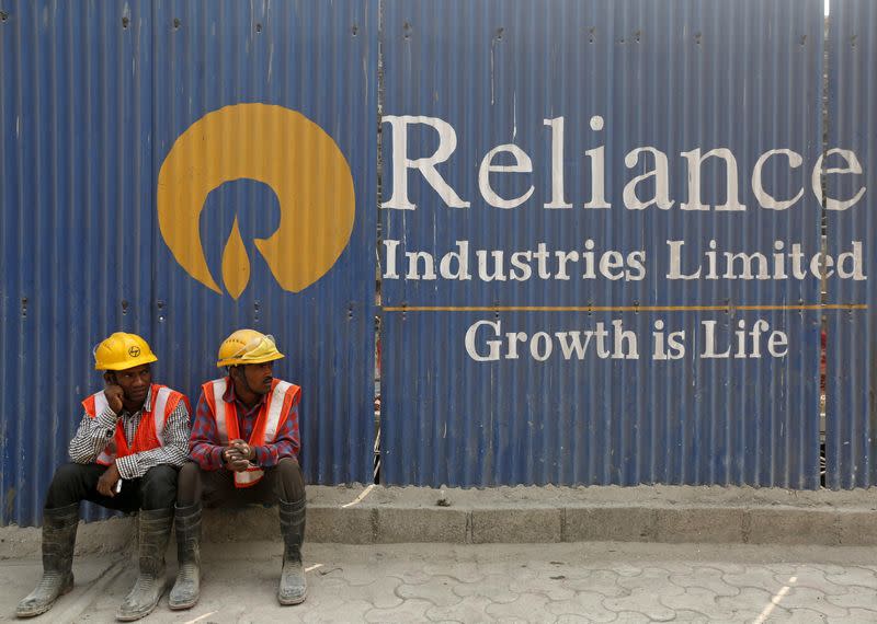 FILE PHOTO: FILE PHOTO: Labourers rest in front of an advertisement for Reliance Industries in Mumbai