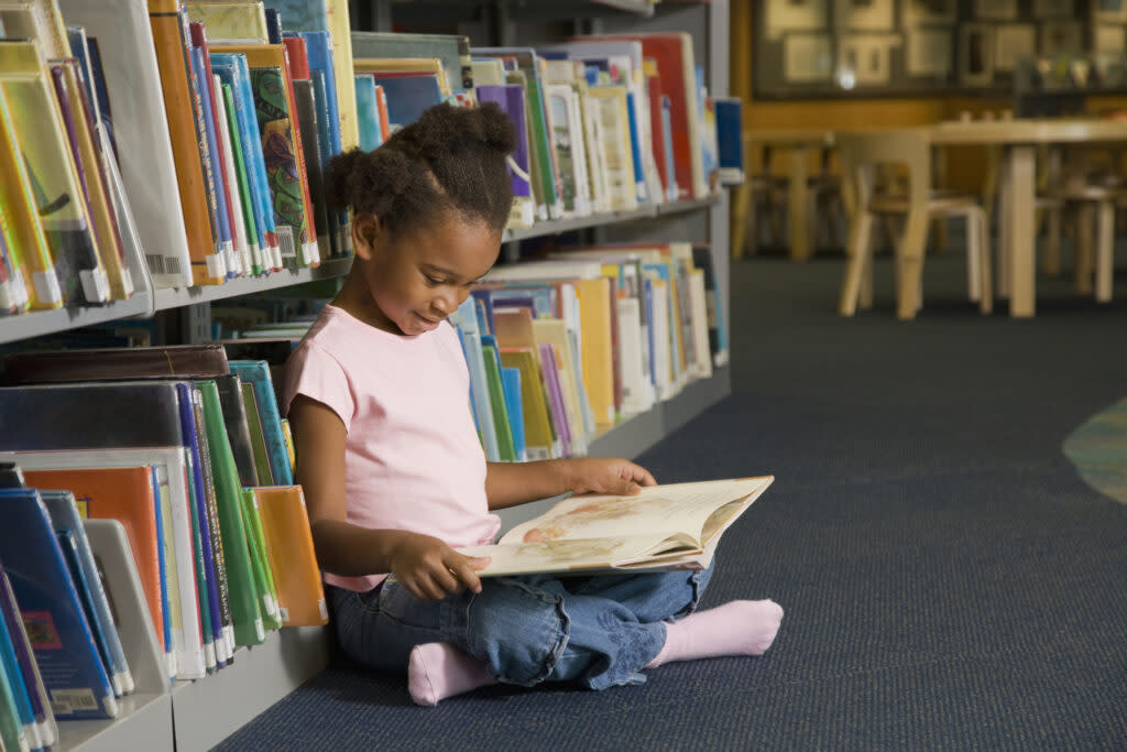 Young girl reading library book in the library