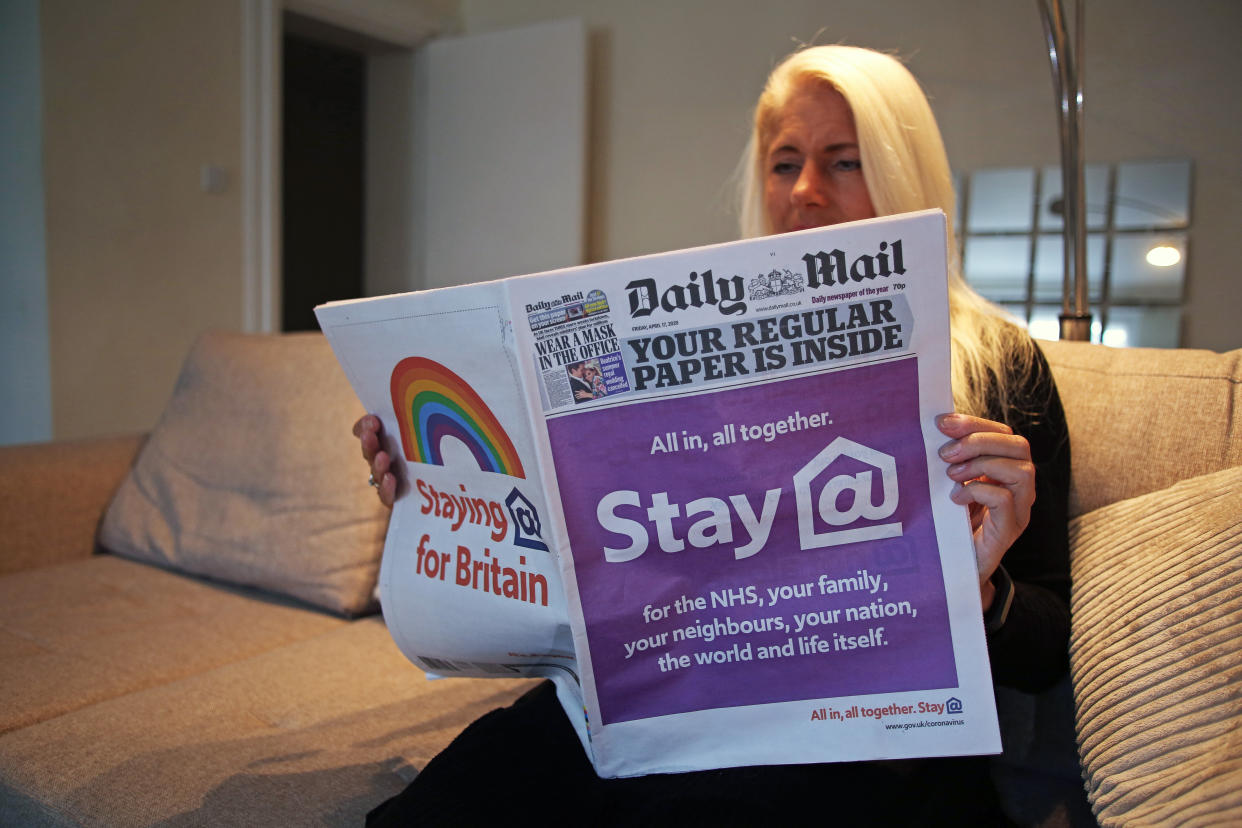 A woman reads a special edition of the Daily Mail newspaper, which displays a NHS coronavirus message on the front pages saying 'All in, all in together. Stay at home' and 'staying home for Britain' as the UK continues in lockdown to curb the spread of coronavirus.