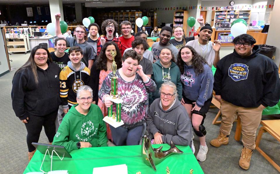 The Dennis-Yarmouth Unified Sports team with coaches and partners celebrate with their undefeated trophy in the school library on Dec. 13.