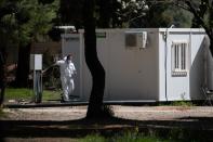 A man wearing a protective suit and a face mask makes his way in the Ritsona migrant camp after authorities found 20 coronavirus cases and placed the camp under quarantine, following the outbreak of coronavirus disease (COVID-19), in Ritsona