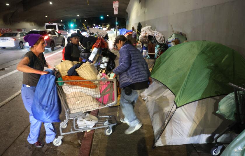 Hollywood, California February 22, 2024-Jovette Cutaiar, left, gets help with a grocery cart after doing laundry at a homeless encampment under the 101 freeway on Cahuenga Blvd. in Hollywood. (Wally Skalij/Los Angeles Times)