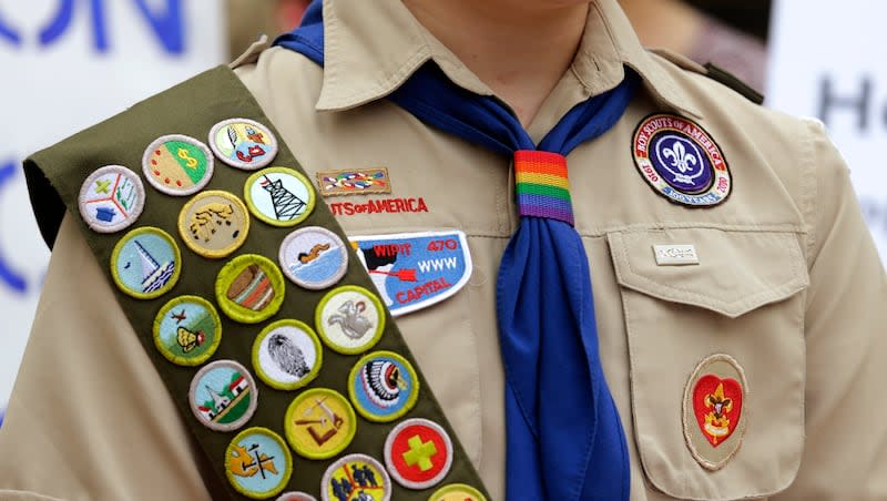 Merit badges and a rainbow-colored neckerchief slider are affixed on a Boy Scout uniform outside the headquarters of Amazon in Seattle. The U.S. organization, which now welcomes girls into the program and allows them to work toward the coveted Eagle Scout rank, announced Tuesday, May 7, 2024, that it will change its name to Scouting America as it focuses on inclusion.