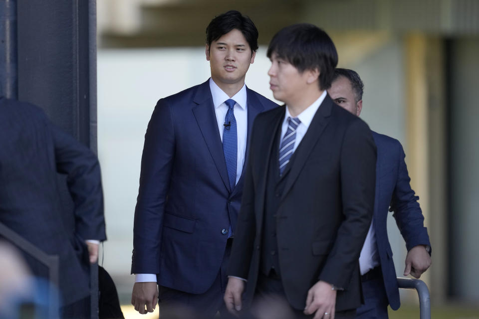 Los Angeles Dodgers' Shohei Ohtani, left, walks onto the stage behind interpreter Ippei Mizuhara during a baseball news conference at Dodger Stadium Thursday, Dec. 14, 2023, in Los Angeles. (AP Photo/Ashley Landis)