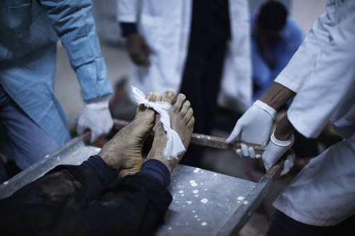 Personnel at the Brega hospital morgue prepare the body of a Libyan rebel fighter brought out from the battle for Ras Lanuf