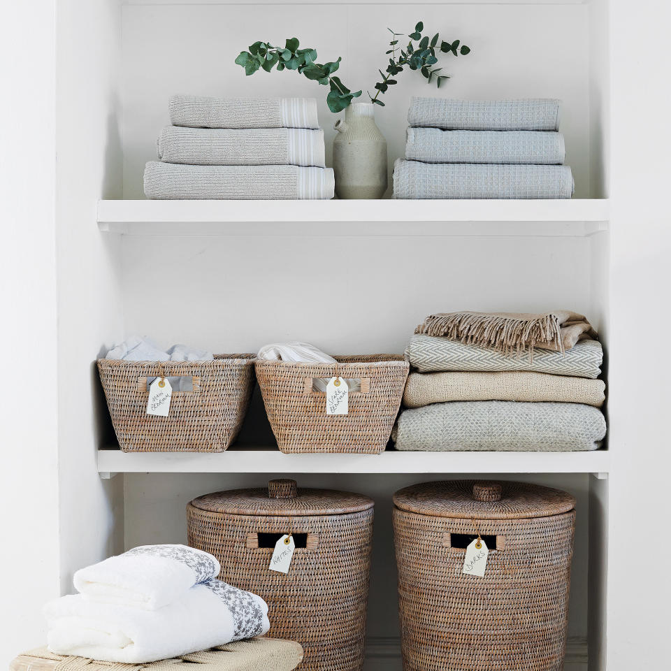  Linen cupboard with folded towels and labelled storage baskets. 