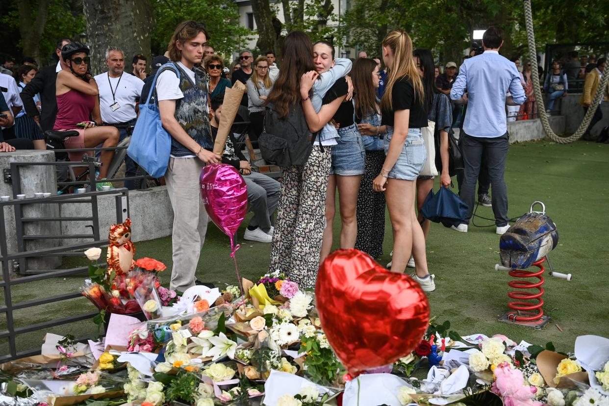 Recueillement de personnes autour des fleurs déposées en hommage aux victimes de l’attaque au couteau d’Annecy.