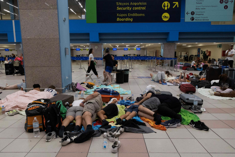 Tourists sleep as they wait for departing planes at the airport, after being evacuated following a wildfire on the island of Rhodes, Greece, July 24, 2023. REUTERS/Nicolas Economou