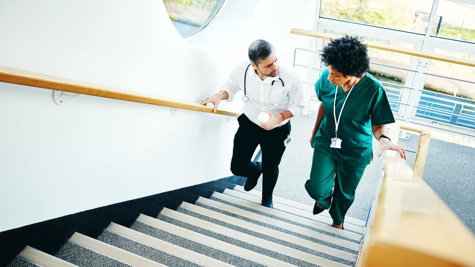 Two medical doctors on staircase having conversation over a case in hospital.