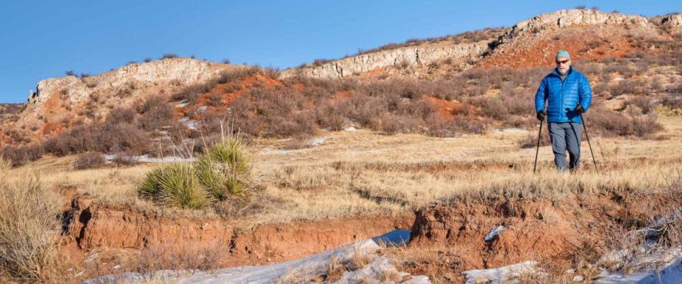 senior make is hiking with trekking poles at Colorado foothills of Rocky Mountains - Red Mountain Open Space, a popular hiking, biking and horse riding area near Fort Collins