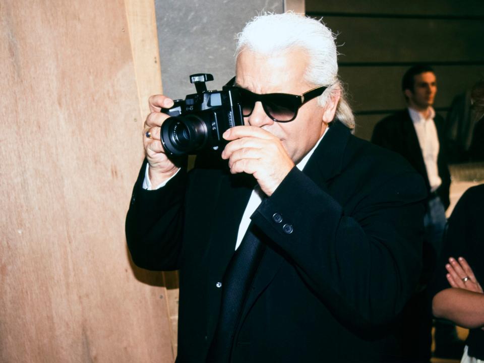 Karl Lagerfeld takes a photo with a camera in 1997