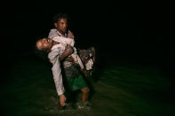 <p>Sona Banu gets carried by Nobi Hossain to the shore of the Naf river as hundreds of Rohingya arrive by boats in the safety of darkness on September 27, on Shah Porir Dwip island, Cox’s Bazar, Bangladesh. (Photograph by Paula Bronstein/Getty Images) </p>