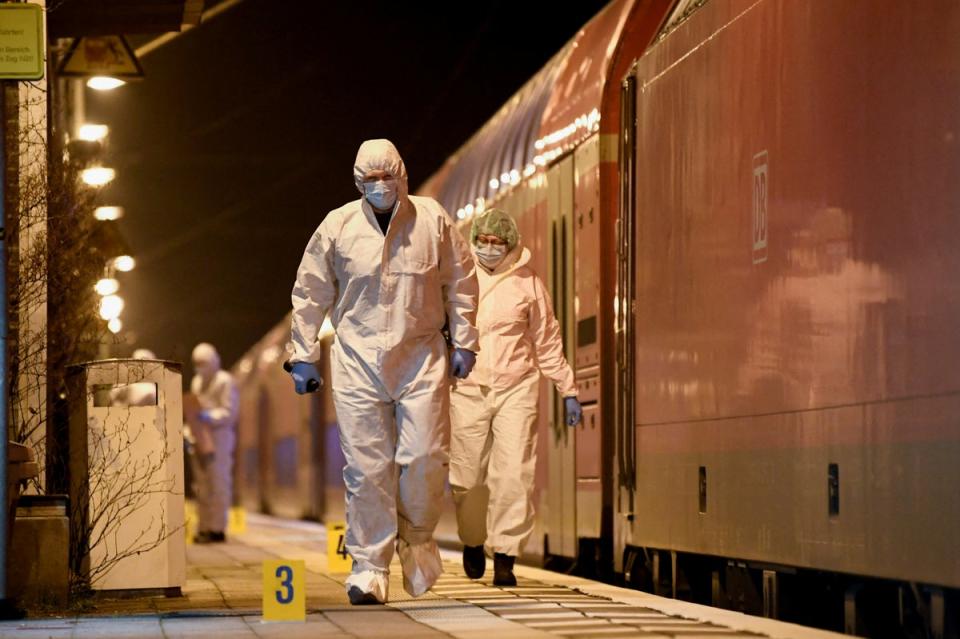 Forensic experts walk next to the train at a railway station in Brokstedt, Germany (REUTERS)