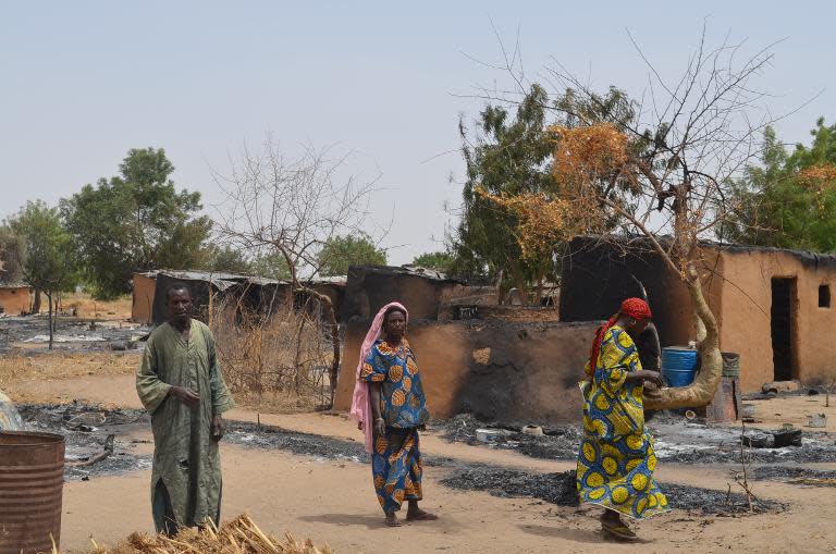 File photo shows villagers walking through razed homes in Mainok, outside Maiduguri in Borno State, northeast Nigeria, on March 6, 2014