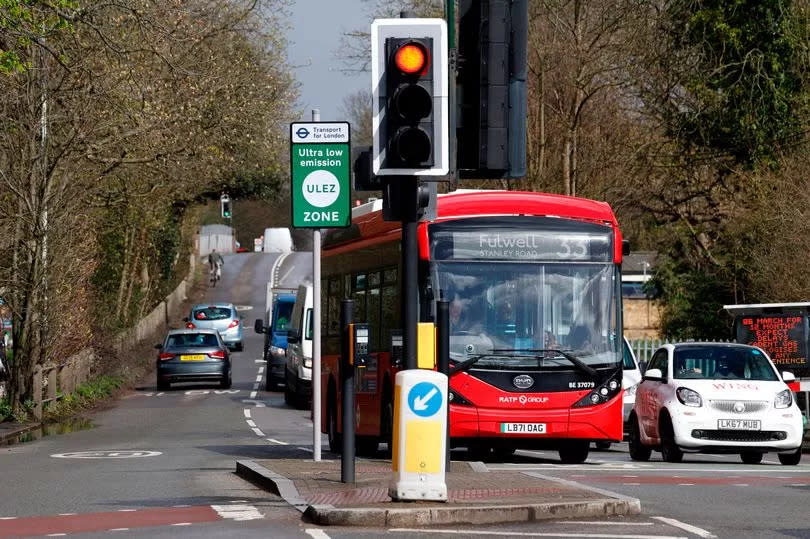 Cars and a bus on a road with a ULEZ sign in London