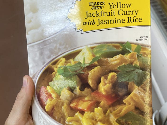 hand holding package of trader joe's yellow jackfruit curry with jasmine rice