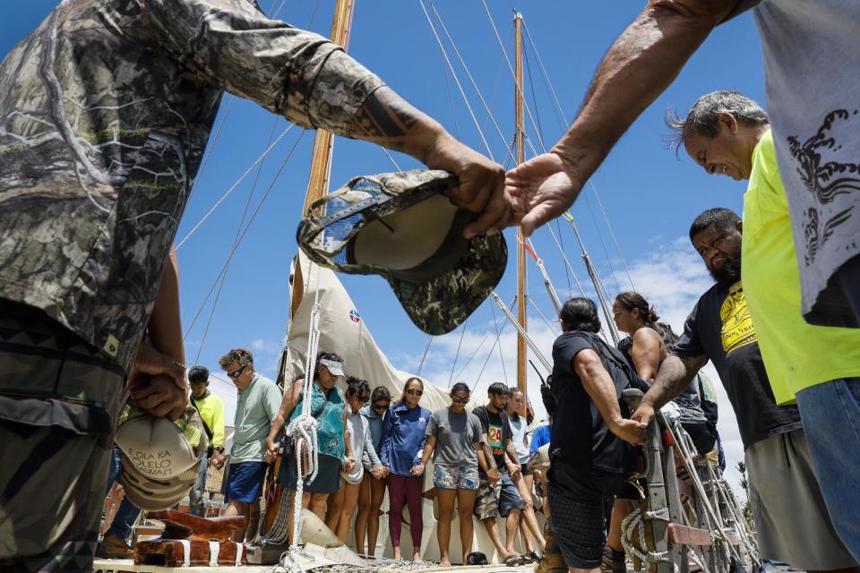 Volunteers join hands in prayer after delivering a boatload of supplies for Lahaina fire victims