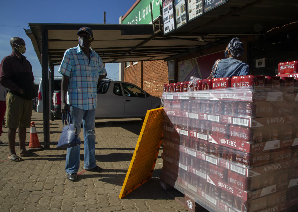 Customers queue to purchased alcohol beverages outside the Sam Liquor Store in Thokoza township, near Johannesburg, South Africa, Monday, June 1, 2020. Liquor stores have reopened Monday after being closed for over two months under lockdown restrictions in a bid to prevent the spread of coronavirus. (AP Photo/Themba Hadebe)