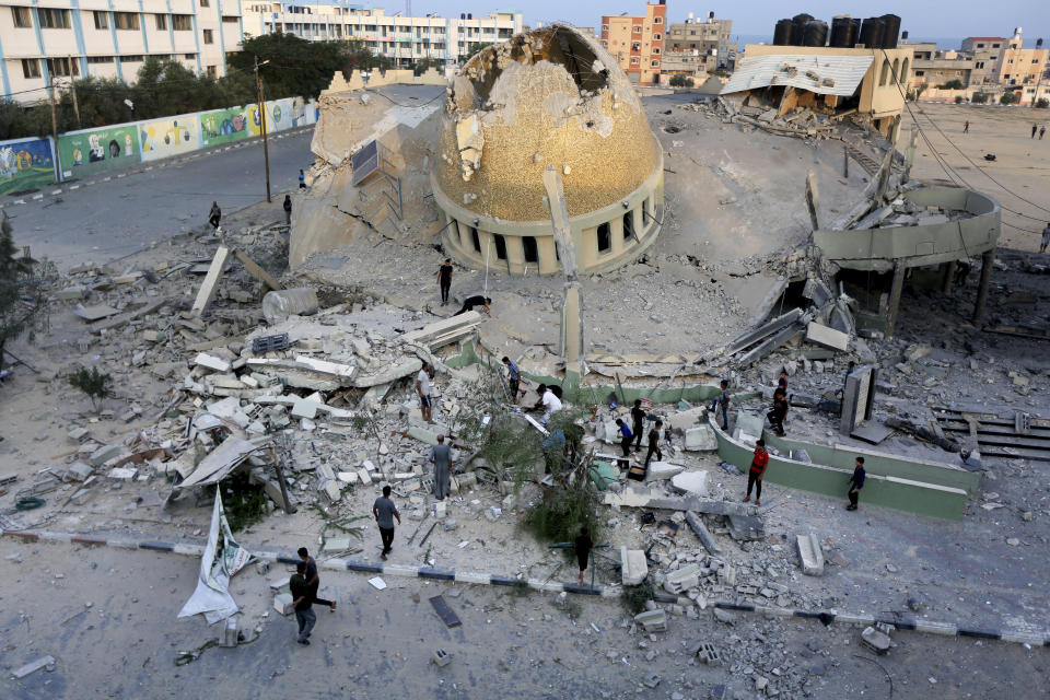 People stand outside a mosque destroyed in an Israeli air strike in Khan Younis, Gaza Strip, Sunday, Oct.8, 2023. The Hamas militants broke out of the blockaded Gaza Strip and rampaged through nearby Israeli communities, taking captives, while Israel's retaliation strikes leveled buildings in Gaza. (AP Photo/Yousef Masoud)