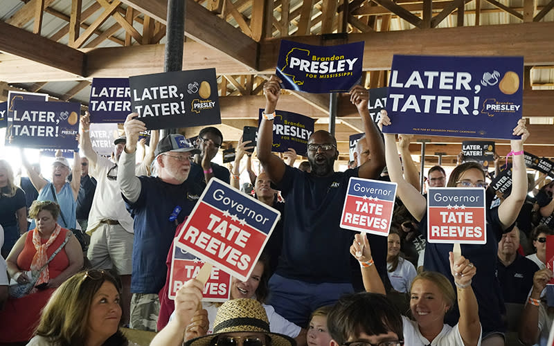 Contrasting groups of supporters for the incumbent Mississippi Gov. Tate Reeves and Democrat Brandon Presley wave their respective candidates' signs. Some of the signs read "Later, Tater!" and others read "Governor Tate Reeves"