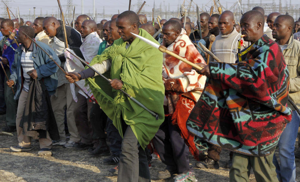 Striking miners sing, chant, march and dance with crudely made weapons and machetes at the Lonmin mine near Rustenburg, South Africa, Wednesday Aug. 15, 2012. Ongoing violence that started last Friday has seen 10 people killed, with no end to the strike in sight. (AP Photo/Denis Farrell)