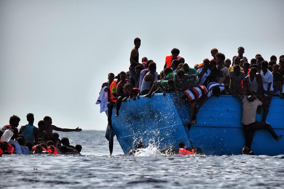 Migrants hang from a boat as they wait to be rescued as they drift in the Mediterranean Sea, some 12 nautical miles north of Libya, on October 4, 2016. At least 1,800 migrants were rescued off the Libyan coast, the Italian coastguard announced, adding that similar operations were underway around 15 other overloaded vessels. / AFP / ARIS MESSINIS        (Photo credit should read ARIS MESSINIS/AFP/Getty Images)