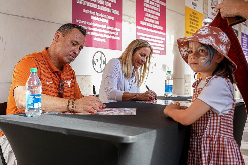 Texas football coach Steve Sarkisian and women's swimming and diving coach Carol Capitani sign autographs during the school's SEC Celebration on Sunday. The Longhorns officially joined the conference Monday, and the focus is on the football team, which enters the year with high expectations and a No. 3 preseason national ranking.