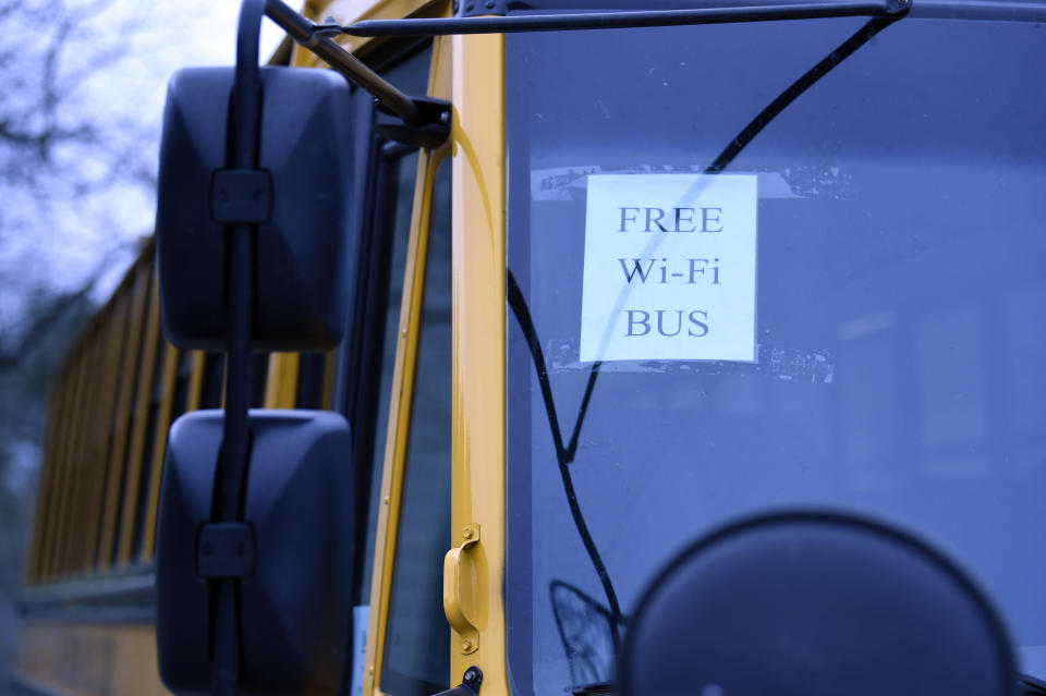 In this Thursday, March 26, 2020, photo, this wi-fi-enabled school bus, seen at an apartment complex in Winnsboro, S.C., is one of many being sent to rural and lower-income areas around South Carolina to help students with distance learning during the new coronavirus outbreak. With routers mounted inside, the buses broadcast enough bandwidth in an area the size of a small parking for parents to drive up and children to access the internet from inside their cars. (AP Photo/Meg Kinnard)