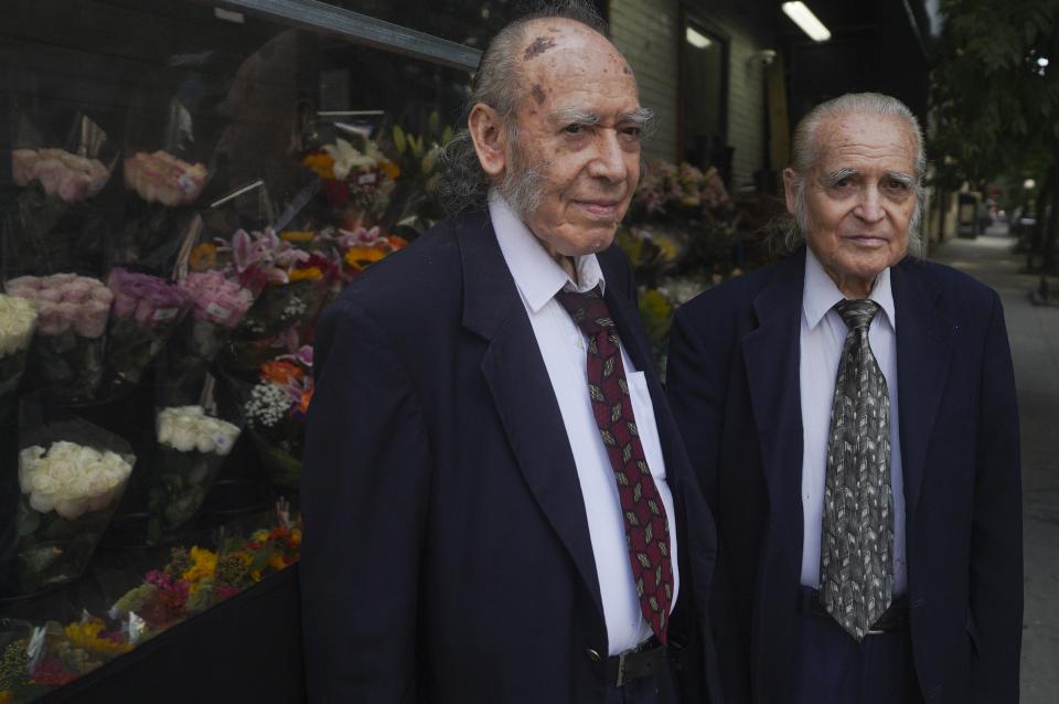 Octogenarian brothers from Ecuador, Carlos Cevallos, left, and Miguel Cevallos, together during a press meeting, Monday Aug. 29, 2022, in New York. For years the Cevallos brothers made a living drawing posters for nightclubs, taco trucks and restaurants, attracting clients by word of mouth, but an Instagram account changed a lot of that. (AP Photo/Bebeto Matthews)