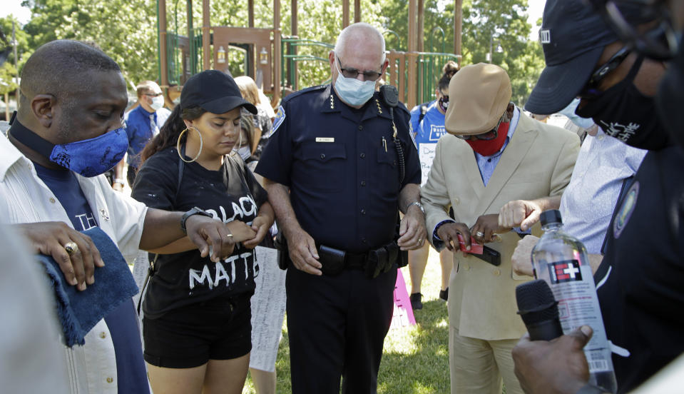 Local Pastors touch elbows with Fairfield Police Chief Walter Tibbet, center, during 'Taking a knee for Justice and Prayer' service, Wednesday, June 3, 2020, in Fairfield, Calif. (AP Photo/Ben Margot)