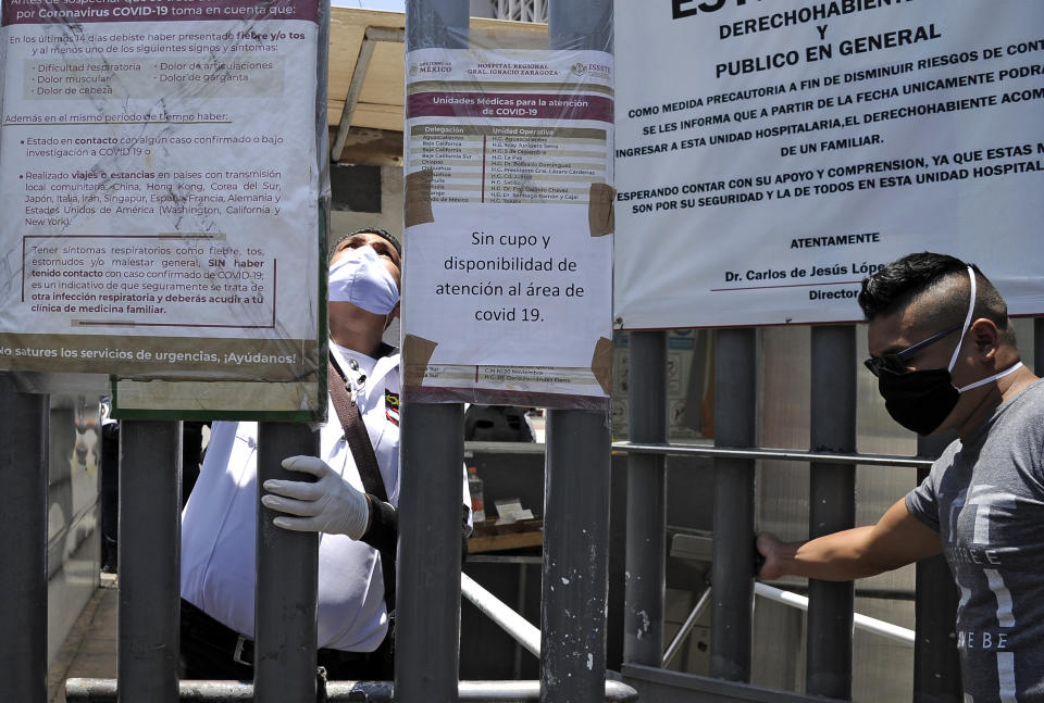 Employees are seen at the entrance of the Zaragoza Hospital, where a sign reads No place or availability for assistance at the COVID-19 area, in Mexico City on May 06, 2020. - The desperate search for hospitals and the lack of medical reports deepens the distress of relatives of COVID-19 patients in Mexico. (Photo by CLAUDIO CRUZ / AFP) (Photo by CLAUDIO CRUZ/AFP via Getty Images)